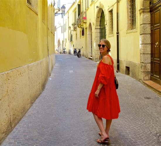 Beautiful Verona. Fashion Blogger Girl by Style Blog Heartfelt Hunt. Girl with two blond pigtail braids wearing an off-shoulder dress, Ray-Ban sunglasses, Louis Vuitton bag and sandals.