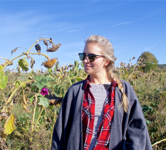 Beauty of Nature. Fashion Blogger Girl by Style Blog Heartfelt Hunt. Girl with blond dutch braid wearing a cape, plaid shirt, striped top, destroyed jeans, Ray-Ban sunglasses and boots.