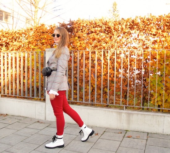 Belt Bag. Fashion Blogger Girl by Style Blog Heartfelt Hunt. Girl with blond hair wearing a belt bag, checked blazer, black turtleneck sweater, blouse with trumpet sleeves, red jeans, round Ray-Ban sunglasses and white boots.