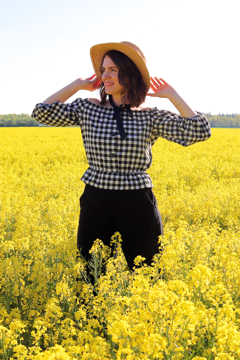 Canola Love. Fashion and Style Blog Girl from Heartfelt Hunt. Girl with blonde beach waves wearing an off-shoulder gingham blouse, black culotte, straw hat and straw bag.