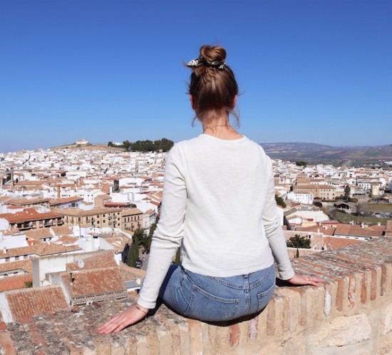 Day Trip Antequera. Fashion Blogger Girl by Style Blog Heartfelt Hunt. Girl with blond high messy bun and leopard print scrunchie wearing a trench coat, T-shirt, mom jeans, Ray-Ban sunglasses, Rebecca Minkoff backpack and chunky sneakers.