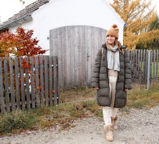 Down Coat. Fashion Blogger Girl by Style Blog Heartfelt Hunt. Girl with blond hair wearing a down coat, pompom beanie, scarf, chunky sweater, corduroy pants, Louis Vuitton backpack and faux fur boots.