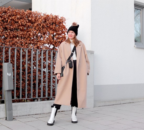 Elevated Sweatpants Look. Fashion Blogger Girl by Style Blog Heartfelt Hunt. Girl with blond hair wearing a camel coat, pompom beanie, turtleneck sweater, sweatpants, 90s bag and white boots.
