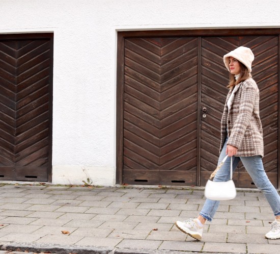 Faux Fur Bucket Hat. Fashion Blogger Girl by Style Blog Heartfelt Hunt. Girl with blond hair wearing a faux fur bucket hat, plaid blazer, white turtleneck, mom jeans, white bag and faux fur sneakers.