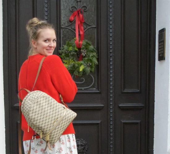 Floral Holiday Season Look. Fashion Blogger Girl by Style Blog Heartfelt Hunt. Girl with blond, high messy bun wearing a floral dress, red sweater, Michael Kors backpack and booties.