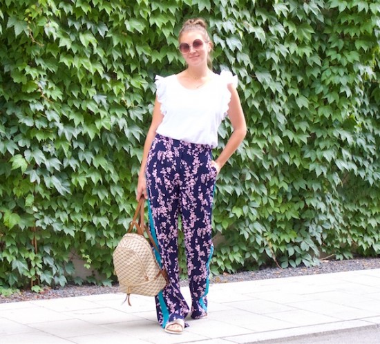 Floral Pants. Fashion Blogger Girl by Style Blog Heartfelt Hunt. Girl with blond, high messy bun wearing floral pants, ruffled top, Michaels Kors backpack and golden sandals.