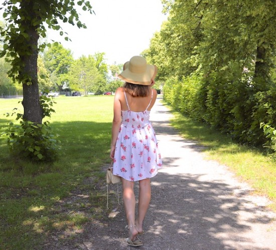 Floral Summer Dress. Fashion Blogger Girl by Style Blog Heartfelt Hunt. Girl with blond hair wearing a floral summer dress, floppy straw hat, Ray-Ban sunglasses, straw bag and golden sandals.