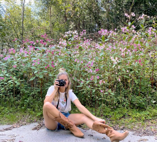 Forest Flowers. Fashion Blogger Girl by Style Blog Heartfelt Hunt. Girl with blond half-up half-down hairstyle with scrunchie wearing a forest flower tee, denim shorts, Ray-Ban sunglasses and cowboy boots.