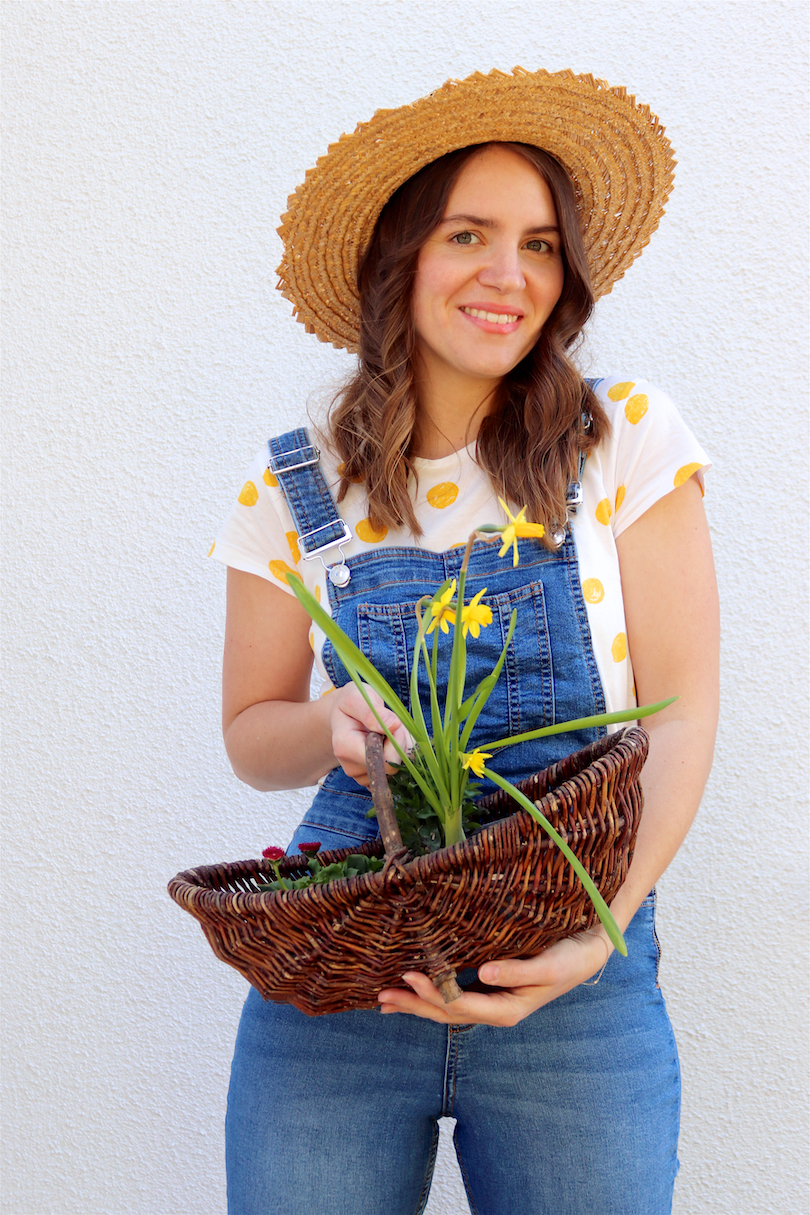 Gardening. Fashion and Style Blog Girl from Heartfelt Hunt. Girl with blonde, loose curls wearing a straw hat, yellow polka dot tee and denim overall.