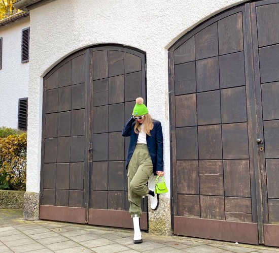 Green Details. Fashion Blogger Girl by Style Blog Heartfelt Hunt. Girl with blond hair wearing a green beanie, white sunglasses, blazer, white turtleneck, cargo pants, green bag and white boots.