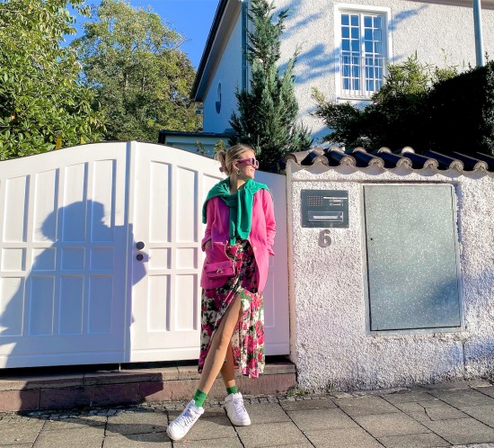 Green Pink. Fashion Blogger Girl by Style Blog Heartfelt Hunt. Girl with blond hair wearing a green sweatshirt, pink blazer, floral dress, pink sunglasses, pink mini bag, green socks and white Nike sneakers.