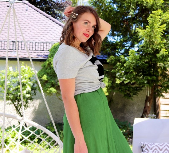 Green Vibes. Fashion Blogger Girl by Style Blog Heartfelt Hunt. Girl with blond loose waves and pearl and gold hair clip wearing a green dress, graphic tee, statement necklace, round straw bag and straw sandals with pompons.