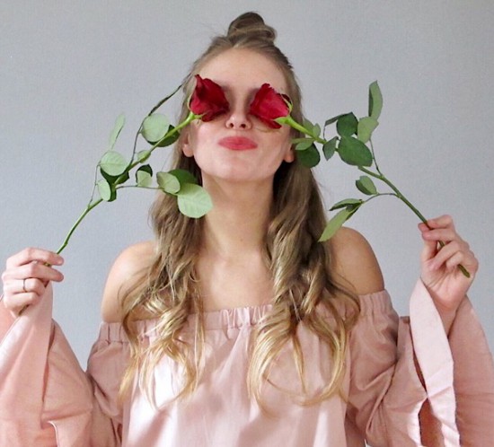 Happy Valentines Day. Fashion Blogger Girl by Style Blog Heartfelt Hunt. Girl with blond, loose curls and half-up half-down bun wearing a light pink off shoulder blouse with ruffled sleeves.