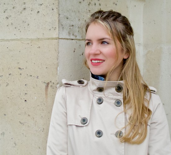 Blonde fashion blogger girl smiling and wearing a trenchcoat