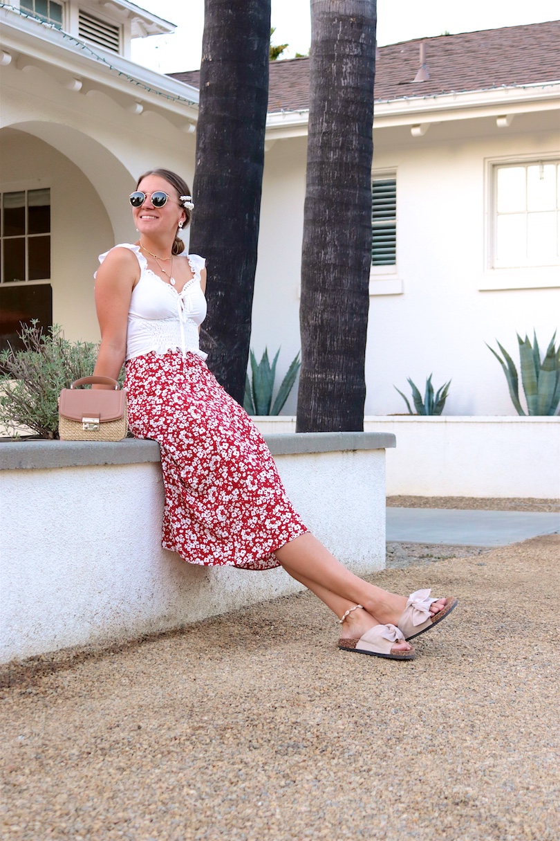 Indian Springs. Fashion Blogger Girl by Style Blog Heartfelt Hunt. Girl with blond, low bun and pearl hair clip wearing Ray-Ban sunglasses, top with ruffles, floral skirt, straw bag and sandals with bow.