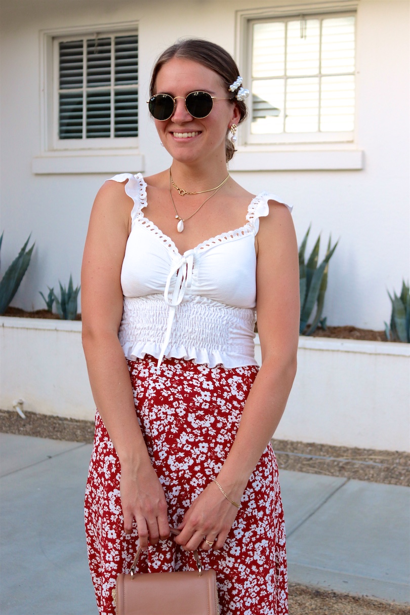 Indian Springs. Fashion Blogger Girl by Style Blog Heartfelt Hunt. Girl with blond, low bun and pearl hair clip wearing Ray-Ban sunglasses, top with ruffles, floral skirt, straw bag and sandals with bow.