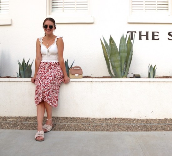 Indian Springs. Fashion Blogger Girl by Style Blog Heartfelt Hunt. Girl with blond, low bun and pearl hair clip wearing Ray-Ban sunglasses, top with ruffles, floral skirt, straw bag and sandals with bow.