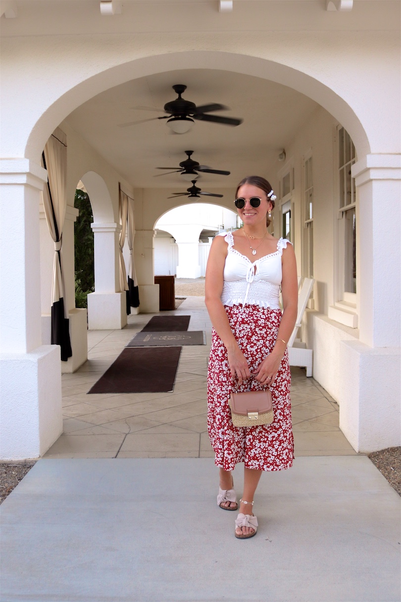 Indian Springs. Fashion Blogger Girl by Style Blog Heartfelt Hunt. Girl with blond, low bun and pearl hair clip wearing Ray-Ban sunglasses, top with ruffles, floral skirt, straw bag and sandals with bow.