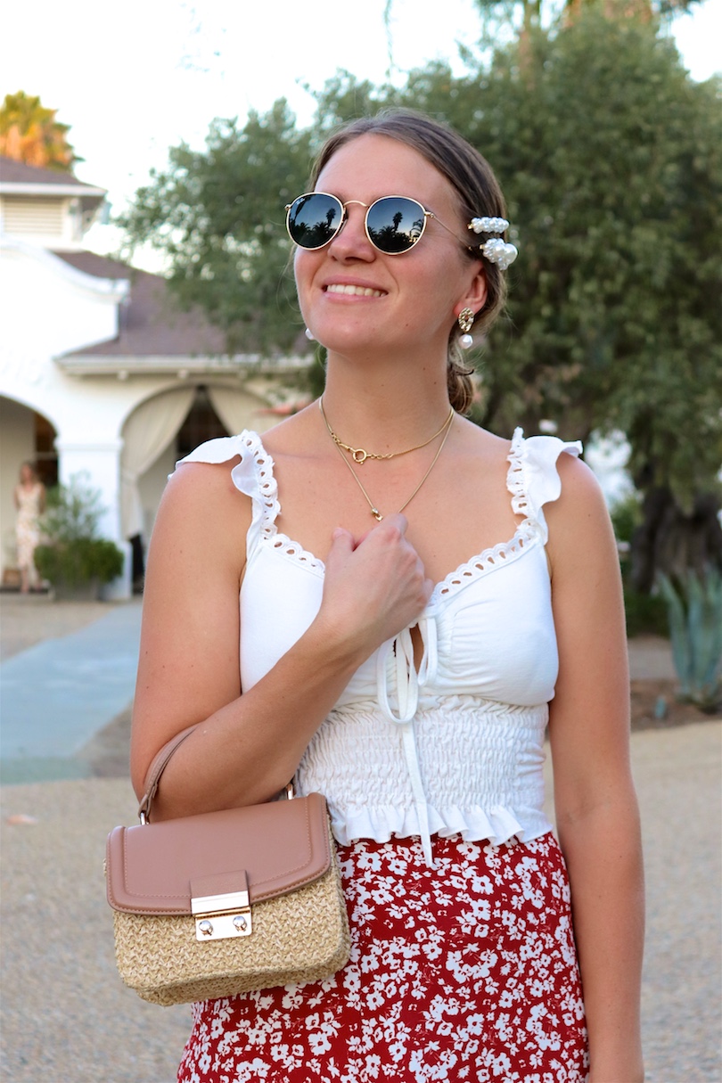 Indian Springs. Fashion Blogger Girl by Style Blog Heartfelt Hunt. Girl with blond, low bun and pearl hair clip wearing Ray-Ban sunglasses, top with ruffles, floral skirt, straw bag and sandals with bow.