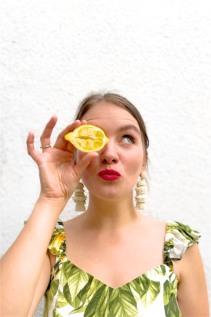 Lemon Print. Fashion Blogger Girl by Style Blog Heartfelt Hunt. Girl with blond, low bun wearing a lemon print top, tassel earrings, straw belt and beige pants.