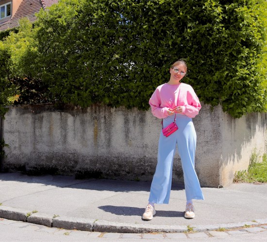 Light Blue Pink. Fashion Blogger Girl by Style Blog Heartfelt Hunt. Girl with blond, low bun wearing light blue pants, pink sweater, pink mini bag, pink sunglasses and chunky sneakers.