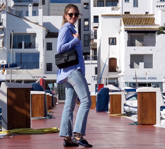 Maritime Stripes. Fashion Blogger Girl by Style Blog Heartfelt Hunt. Girl with blond, long hair wearing a blouse in maritime stripes, cropped flare jeans, Ray-Ban sunglasses, bag and lace up ballet flats.