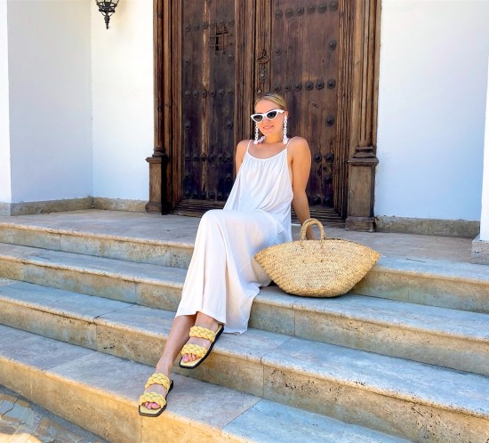 Maxi Summer Dress. Fashion Blogger Girl by Style Blog Heartfelt Hunt. Girl with blond low bun wearing a off-white maxi summer dress, white sunglasses, straw bag and braided sandals.