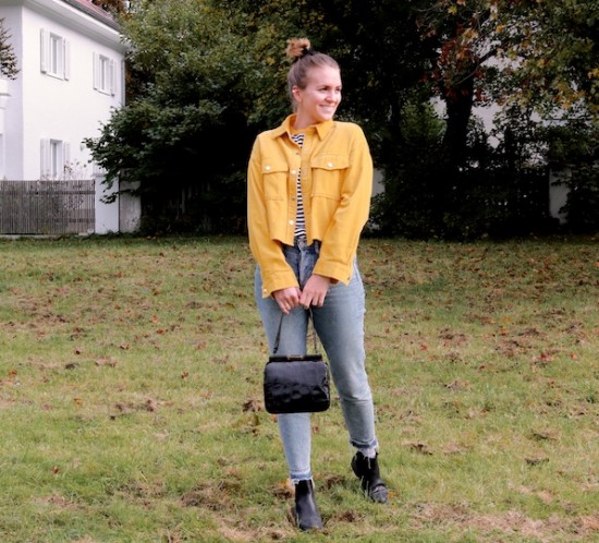 Mustard Corduroy. Fashion Blogger Girl by Style Blog Heartfelt Hunt. Girl with blond, high messy bun and a black velvet scrunchie wearing a mustard corduroy jacket, striped top, mom jeans, black purse and black chelsea boots.