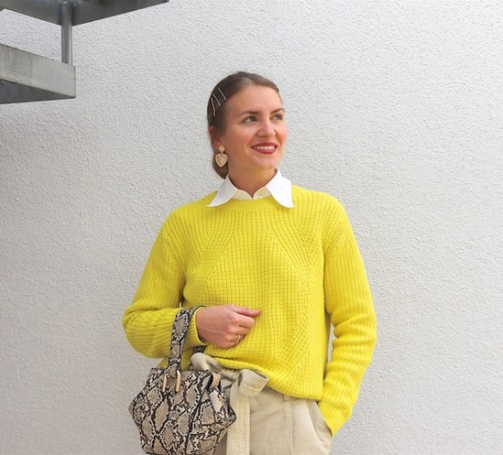Neon Yellow Sweater. Fashion Blogger Girl by Style Blog Heartfelt Hunt. Girl with blond low bun and bobby pins wearing a neon yellow sweater, white blouse, paperbag pants, golden earrings, snake print bag and white boots.