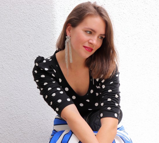 Pattern Mix. Fashion Blogger Girl by Style Blog Heartfelt Hunt. Girl with blond, long bob wearing a polka dot top, striped skirt, rhinestone earrings, belt bag and studded mules.