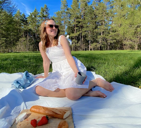 Picnic Day. Fashion Blogger Girl by Style Blog Heartfelt Hunt. Girl with blond, loose curls wearing a white lace dress, slim sunglasses and light blue bag.