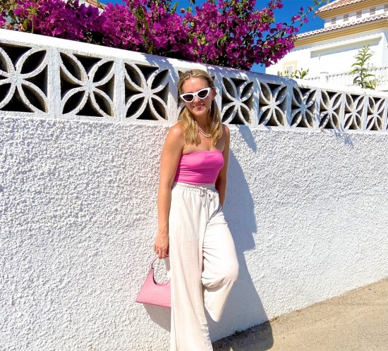 Pink Bag. Fashion Blogger Girl by Style Blog Heartfelt Hunt. Girl with blond braids wearing a pink bag, pink top, white sunglasses, wide leg pants and pink sandals.