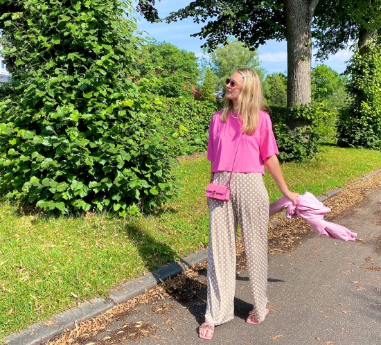 Pink Polka Dots. Fashion Blogger Girl by Style Blog Heartfelt Hunt. Girl with blond hair wearing a pink tee, polka dot pants, pink mini bag, pink sweatshirt and pink sandals.