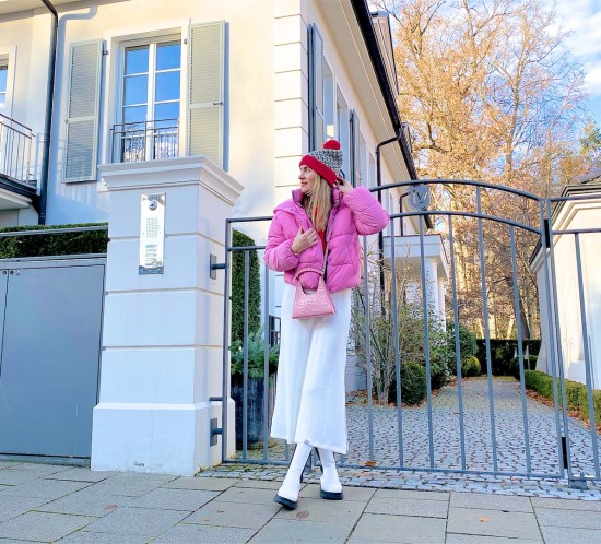 Pink Puffer Jacket. Fashion Blogger Girl by Style Blog Heartfelt Hunt. Girl with blond hair wearing a pink puffer jacket, red sweater, white knit dress, red beanie, pink bag and white boots.