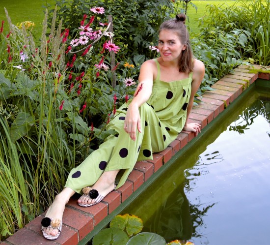 Polka Dot Jumpsuit. Fashion Blogger Girl by Style Blog Heartfelt Hunt. Girl with blond half-up half-down messy bun wearing a polka dot jumpsuit and pompon sandals.