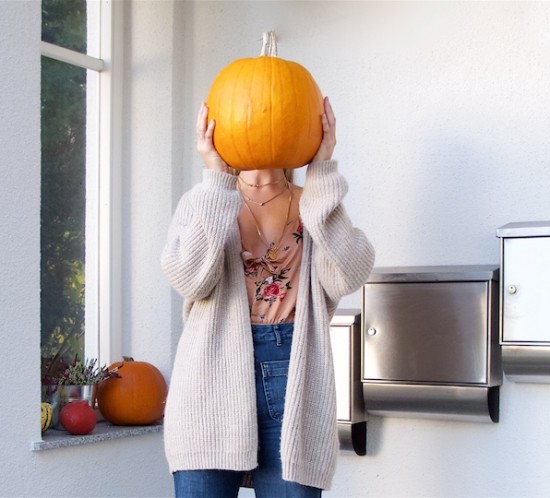 Pumpkin Season. Fashion Blogger Girl by Style Blog Heartfelt Hunt. Girl with blond half-up half-down messy bun wearing a floral dress, chunky cardigan, flared jeans and heels.