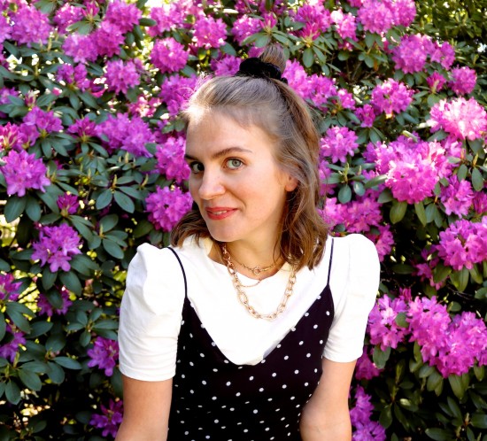 Purple Flower Rain. Fashion Blogger Girl by Style Blog Heartfelt Hunt. Girl with blond half-up half-down hairstyle and black velvet scrunchie wearing a polka dot slip dress, tee with puffed sleeves, statement necklace and Nike sneakers.