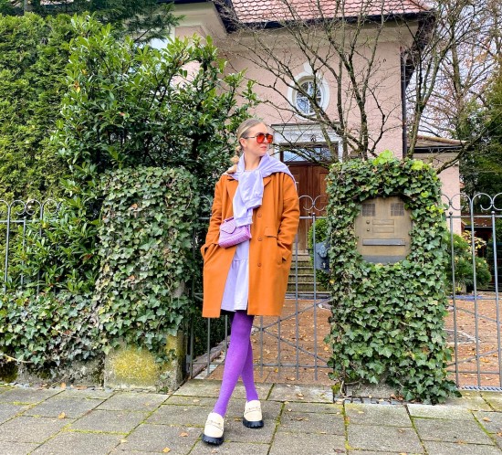 Purple Orange. Fashion Blogger Girl by Style Blog Heartfelt Hunt. Girl with blond bubble ponytail wearing a purple dress, orange coat, purple tights, orange sunglasses, lilac bag and chunky loafers.