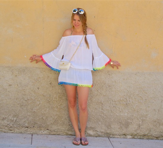 Rainbow Pompons. Fashion Blogger Girl by Style Blog Heartfelt Hunt. Girl with blond side braid wearing a top with rainbow tassels, denim shorts, bikini, sunglasses, vintage Chanel bag and glitter sandals.