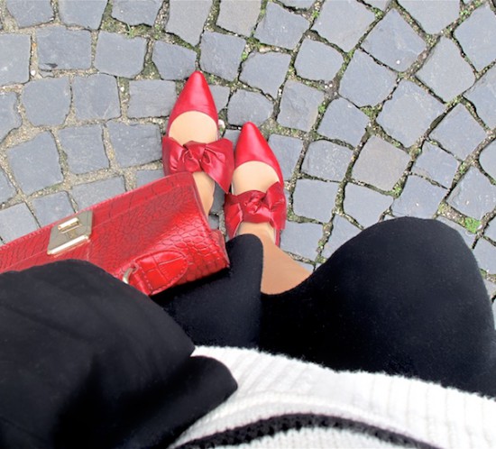 Red Bow Shoes. Fashion Blogger Girl by Style Blog Heartfelt Hunt. Girl with blond, loose curls wearing red bow shoes, striped sweater, top with trumpet sleeves, flared skirt and a red bag.