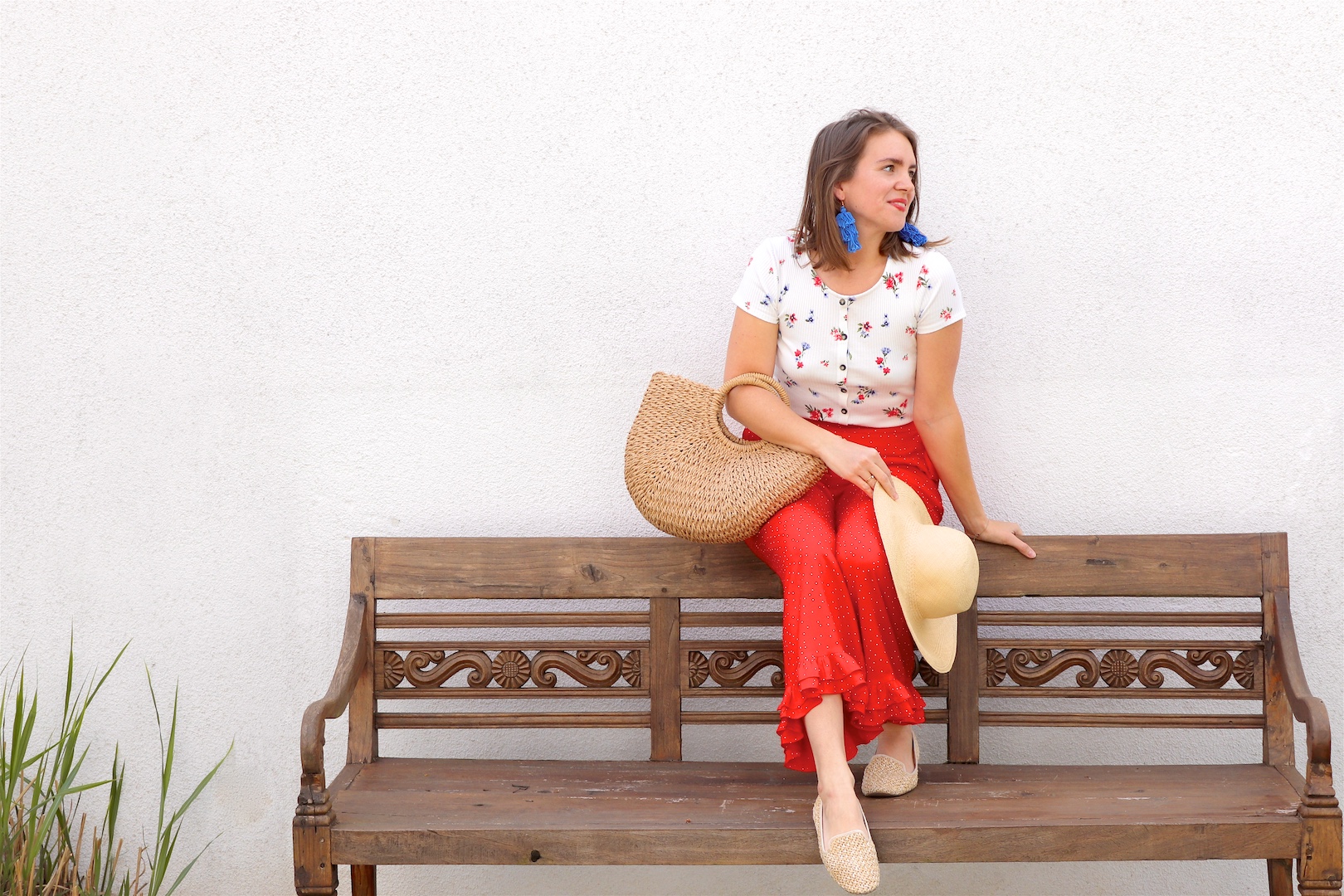 Red Floral. Fashion Blogger Girl by Style Blog Heartfelt Hunt. Girl with blond hair wearing a floral tee, red pants, blue tassel earrings, straw hat, straw bag and straw loafers.