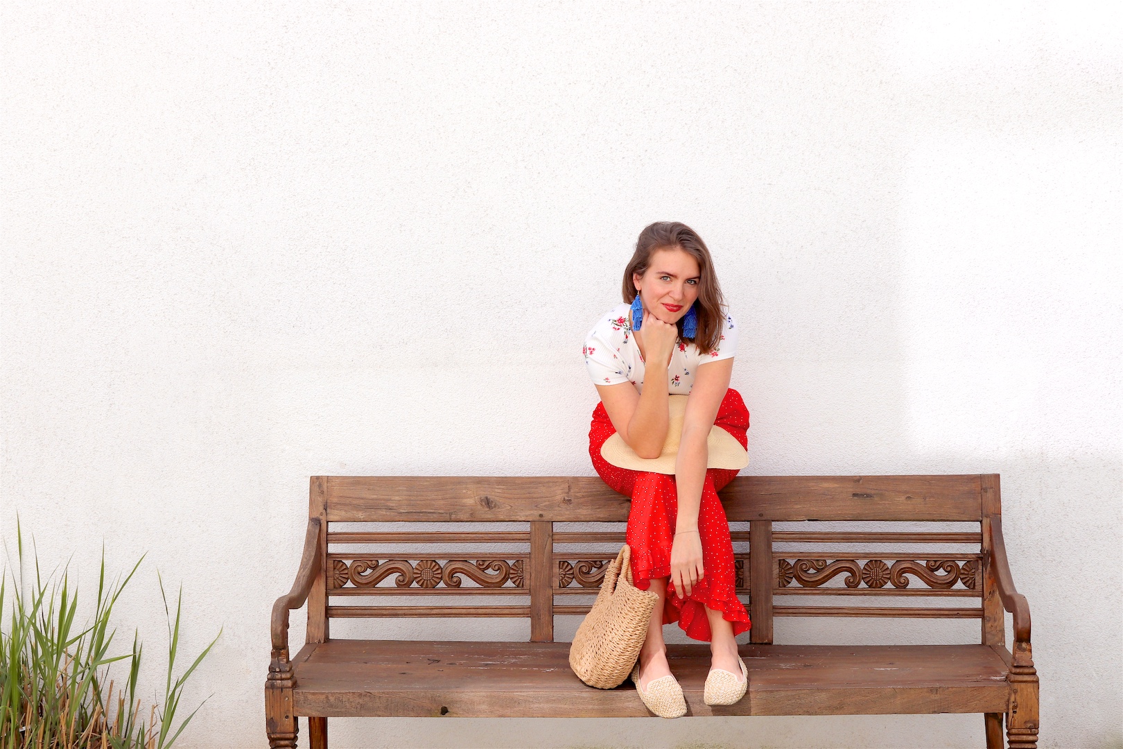 Red Floral. Fashion and Style Blog Girl from Heartfelt Hunt. Girl with blonde hair wearing a floral tee, red pants, blue tassel earrings, straw hat, straw bag and straw loafers.