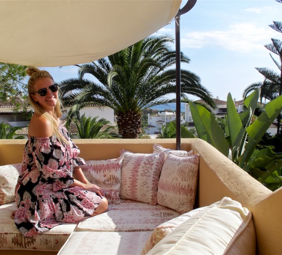 Roof Terrace. Fashion Blogger Girl by Style Blog Heartfelt Hunt. Girl with blond half-up half-down knot wearing an off-shoulder flower dress and Ray-Ban sunglasses.
