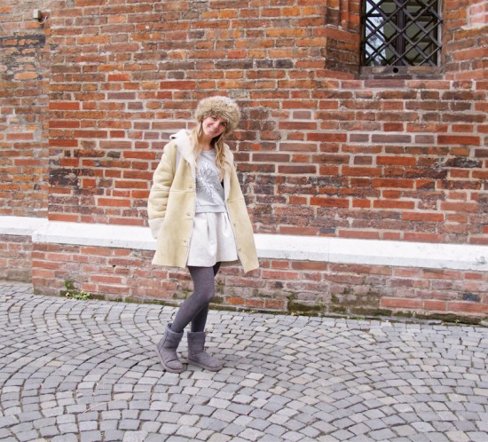 Russian Winter. Fashion Blogger Girl by Style Blog Heartfelt Hunt. Girl with blond loose curls wearing a sweater, brocade skirt, shearling jacket, faux fur beanie, backpack and Ugg boots.