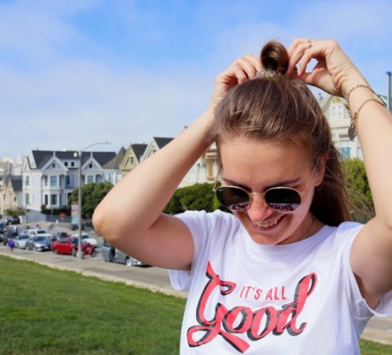 San Francisco. Fashion Blogger Girl by Style Blog Heartfelt Hunt. Girl with blond hair wearing a green shirt, white T-shirt, floral skirt, Ray-Ban sunglasses, belt bag and chunky sneakers.