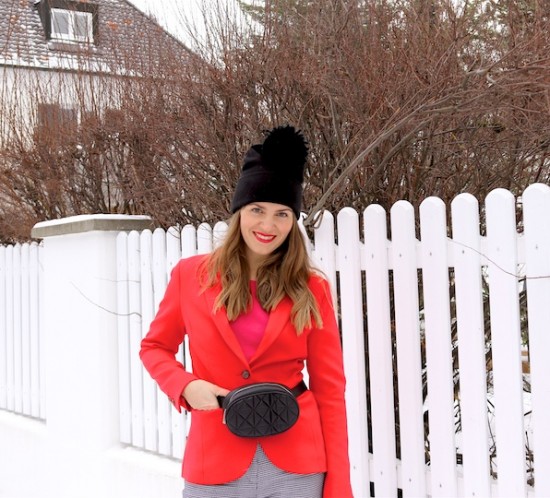 Snowy Valentines Look. Fashion Blogger Girl by Style Blog Heartfelt Hunt. Girl with blond hair wearing a red blazer, pink sweater, houndstooth check pants, beanie, belt bag and sock boots.