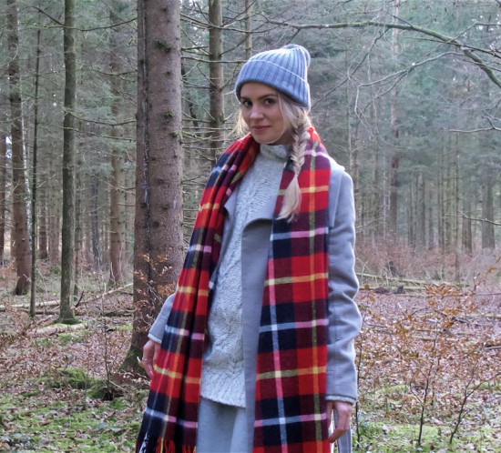 Winter Woods. Fashion Blogger Girl by Style Blog Heartfelt Hunt. Girl with blond fishtail braid wearing a heavy knit sweater, flared skirt, coat, pompom beanie, plaid scarf and Ugg boots.