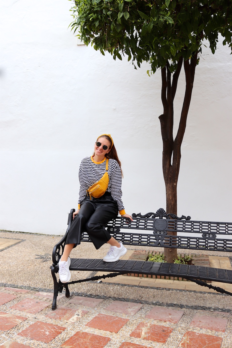 Yellow Belt Bag. Fashion and Style Blog Girl from Heartfelt Hunt. Girl with blonde hair and yellow headband wearing a yellow belt bag, striped top, faux leather culotte, Ray-Ban sunglasses and chunky sneakers.