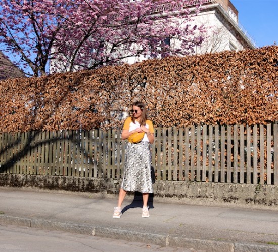 Yellow Spring. Fashion Blogger Girl by Style Blog Heartfelt Hunt. Girl with blond hair wearing a yellow T-shirt, snake print skirt, Ray-Ban sunglasses, hair clip, yellow belt bag and chunky sneakers.